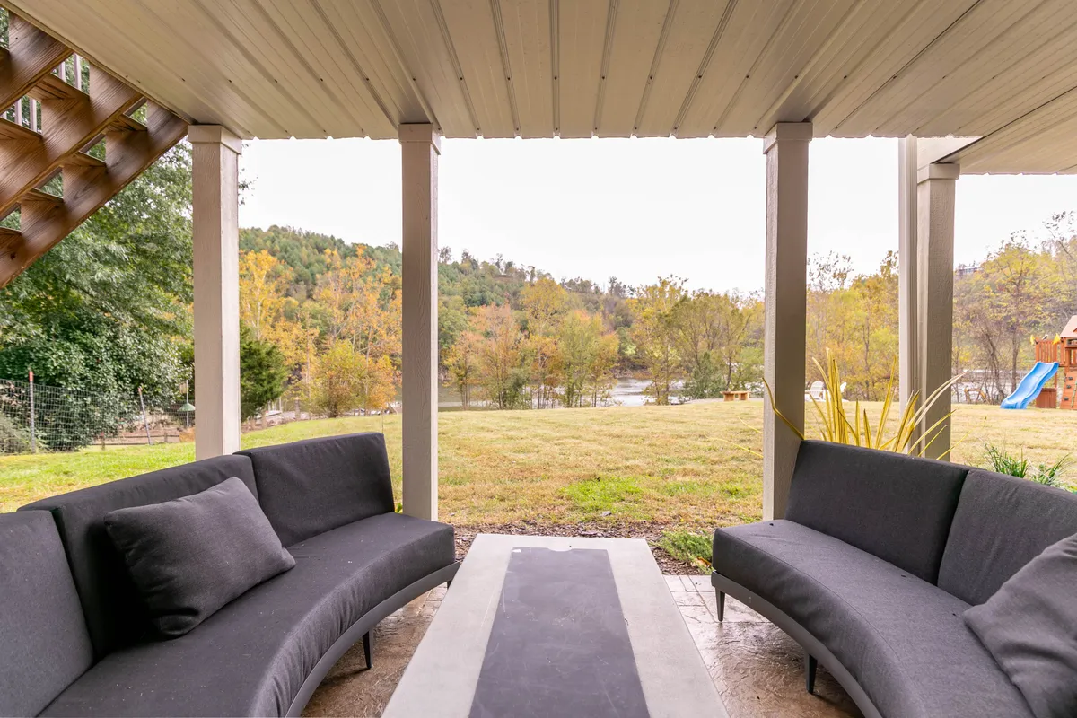 This image captures an outdoor curved seating arrangement and coffee table set against a sweeping view of the surrounding landscape. The lush greenery and open sky evoke the natural beauty that characterizes the mountain environment around Sweet Water Estate.