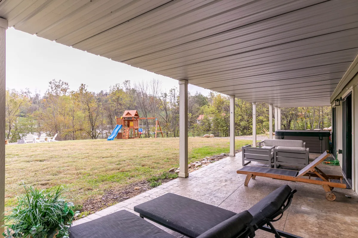This image features a well-equipped outdoor playset surrounded by lush greenery and inviting patio furniture. Children are seen actively playing, while adults relax nearby, creating a scene brimming with family-friendly energy and comfort.